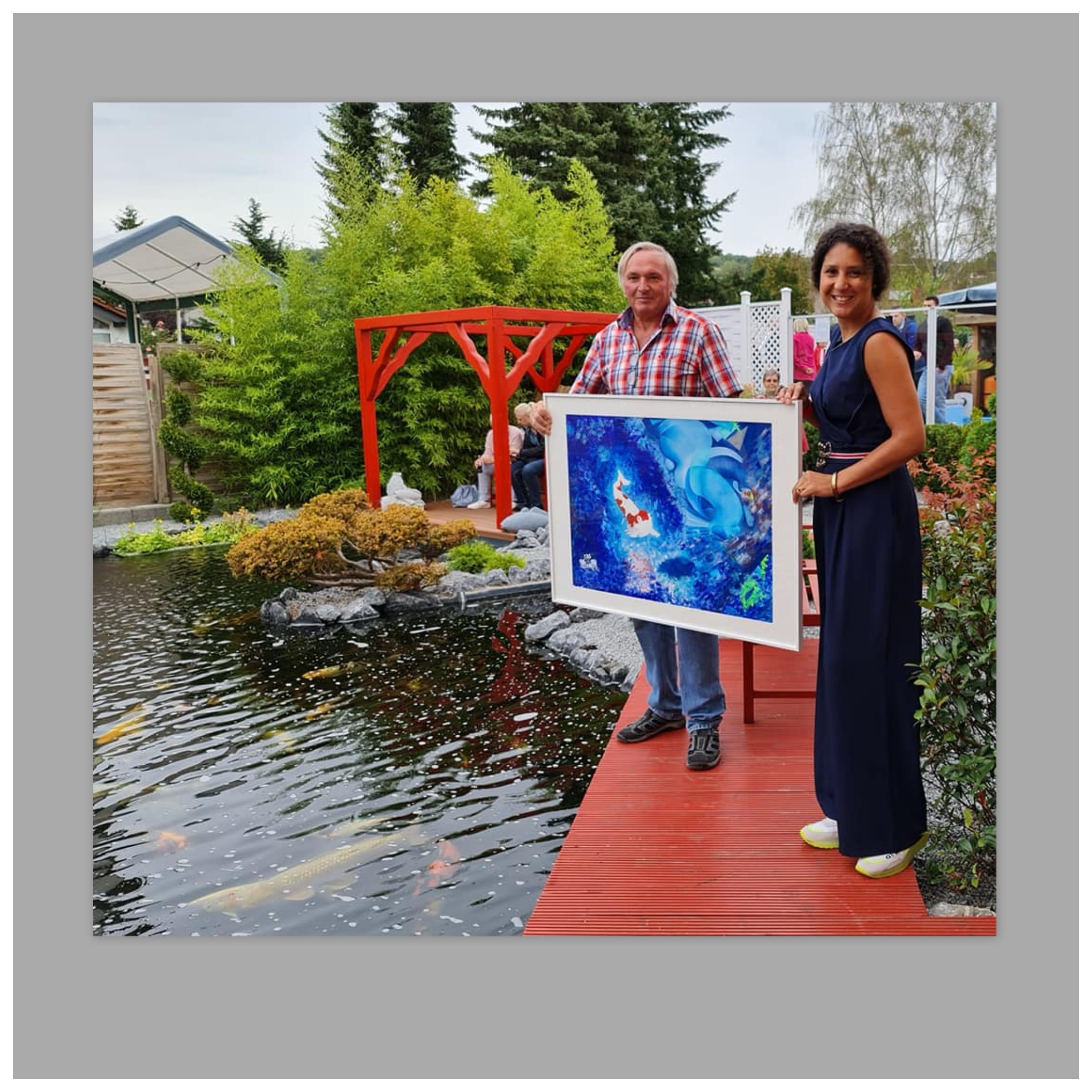 Künstlerin Michaela de Luxe zeigt am Koi Teich Ihr neues Bild mit einem Koi